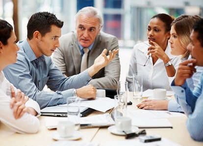 People having a meeting, gathered around a table.